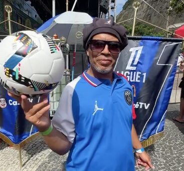 Man dressed in a football jersey spinning a soccer ball on his finger during a Ligue 1 promotional campaign, representing a creative fan activation.